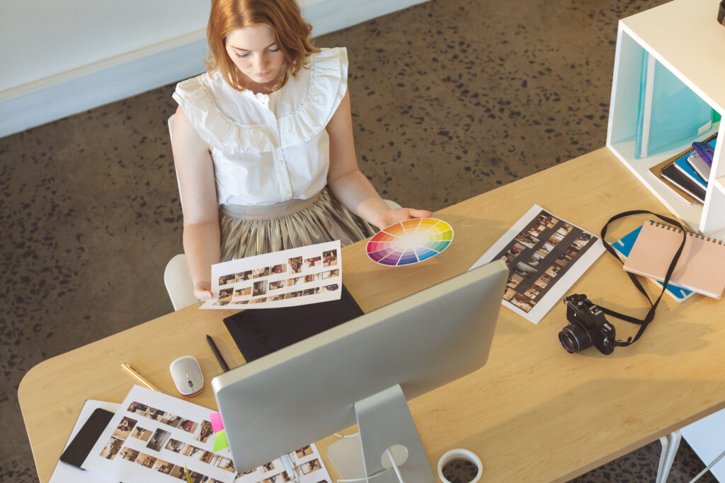 high angle view of young caucasian female graphic designer working at desk in office